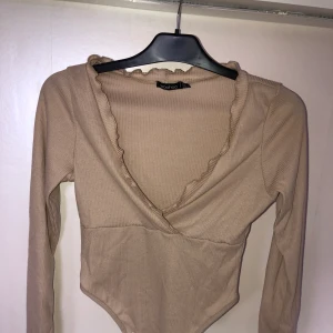 Beige omlott tröja - Beige omlott föredetta body men avklippt till en tröja, från Boohoo, storlek 34/36