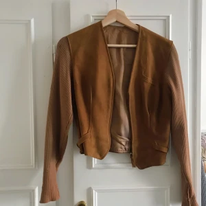 Mockajacka med ribbade ärmar - SÅ FIN jacka i mocka med ribbade ärmar. Något medtagen som ni ser, men västdelen är helt intakt. Passar en XS. 