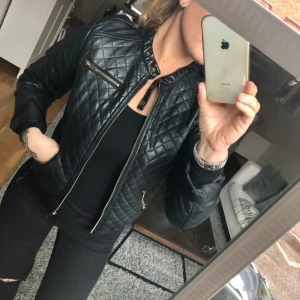 Skinn jacka - Svart Kuiltad konstläder jacka med detaljer i mässing, elegant men samtidigt rockig.