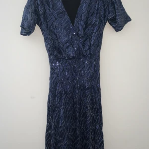 Vacker aftonklänning i paljetter - Mörk blå glittrig paljett maxi aftonklänning  som är använd bara 1 gång på ett bröllop. Midjan är strechig, kortärmad, har lång slits på ena sidan, en kort underkjol. Tyl med paljetter. sitter jättesnygg på. Från Make Way str. 34, passar även str. 36 få den är strecig i midjan. I nyskick.  Köpt för 2500kr.