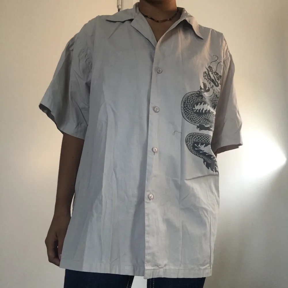 Super cool kortärmad grå skjorta med en drake på! Skön och bra kvalité. Använt endast mågra få gånger. Skickar fler bilder om det önskas 😊 (frakt:44kr)🌸. Skjortor.