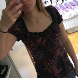  - Blommig blus/tröja med fin snörning där bak och spets vid urringningen 
