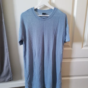 Ljusblå tshirt-klänning  - En tshirt-klänning i ljusblått med glitter 