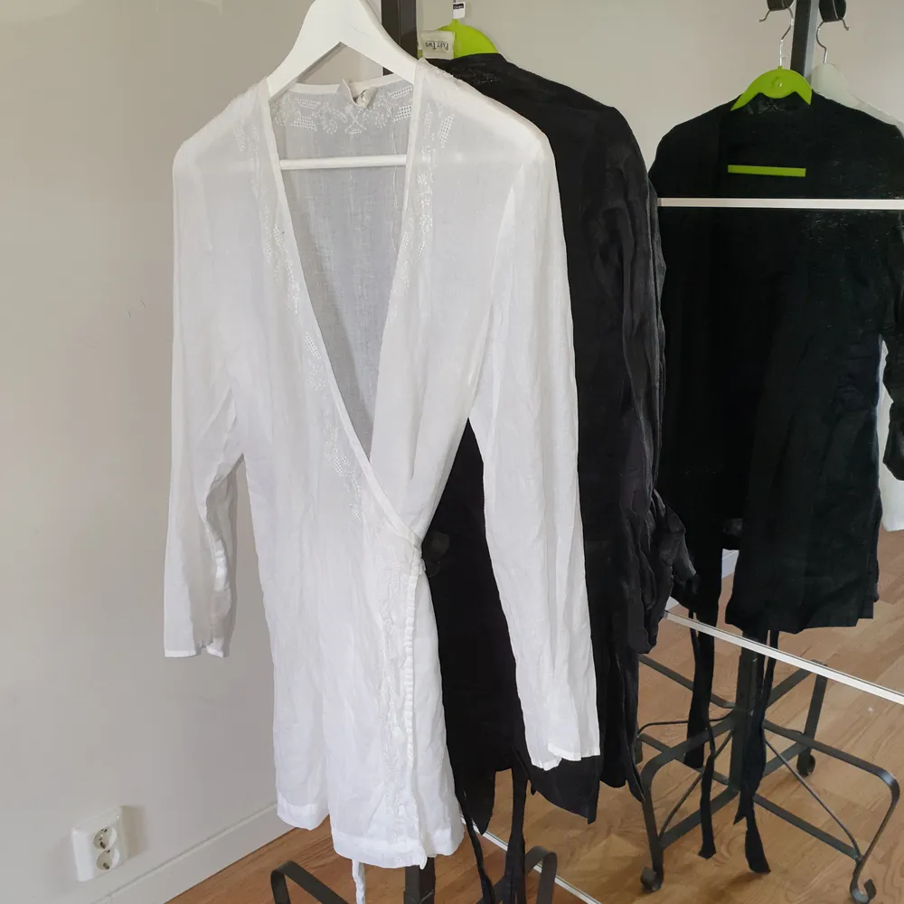 Omlott topp eller kort klänning med brodyr på framsidan finns i både svart eller vit linne. Toppar.