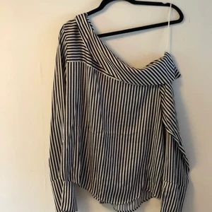 Blus - Svartvit randig blus men en offschoulder. Använd ca 5 gånger. skickar gärna men köpare betalar frakt.