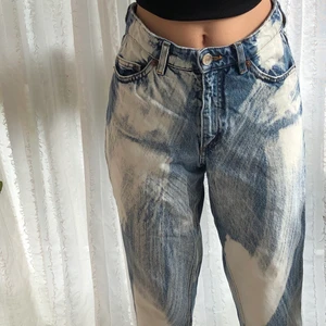 Delvis blekta jeans  - Ett par snygga jeans med blekta ”penseldrag” från monki. De är högmidjade och strl 24. Hon som provar är 168cm. Skriv för fler bilder eller mått.