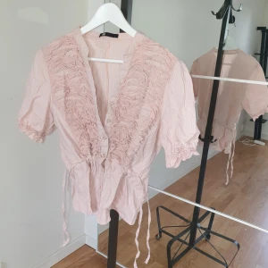 Blus - Rosa blus m krås vid bröstet, dragsko