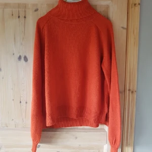  - Stickad orange tröja. Väl använd så den har börjat "noppa" lite (se bild 2), men är utöver det i bra skick, och en mysig tröja! Köparen står för frakt. OBS katt i hemmet.