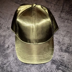  - Khakigrön keps i siden imitation från H&M, ställbar. Oanvänd! 