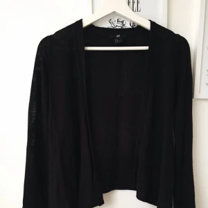  - Svart kofta, något kortare där bak än fram. 