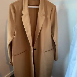 Kappa - Tunn beige/brun kappa från Gina Tricot. Storlek 44 men passar mig som är en 36. Frakt tillkommer