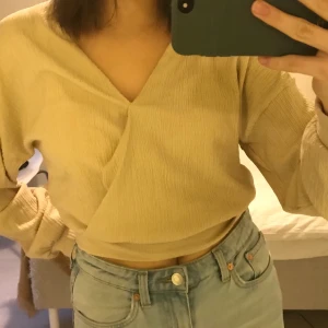 Beige tröja - En festlig beige tröja ifrån Gina Tricot! Lite som en wrap topp i ett stretchigt tyg. Bra skick, säljer då den inte är min stil längre. Kan mötas upp i Stockholm, annars betalar köparen för frakt❤️