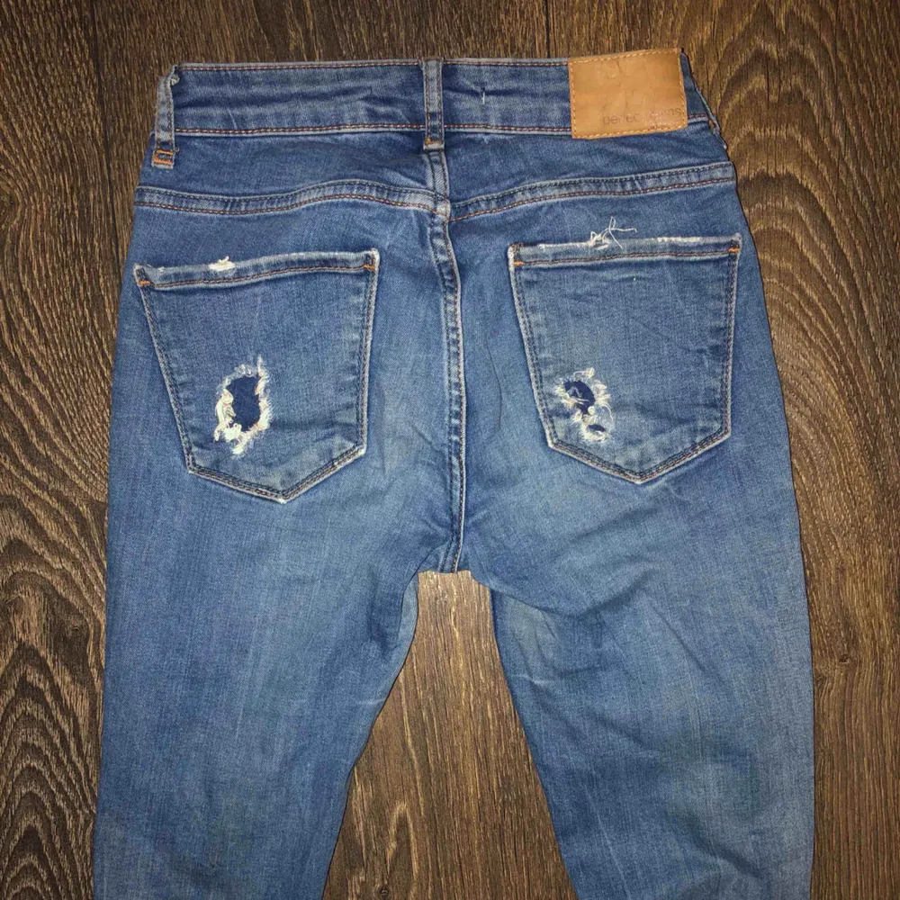 Ett par blåa slitna jeans som är i storlek 25 i midjan och 32 i längd, använda men ändå i bra skick.. Jeans & Byxor.