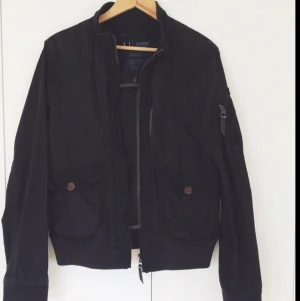  - Svart Armani-jacka i bomull som är ytbehandlad på något sätt. Skön känsla i tyget. Använt ganska lite i en sommar. Dragkedjor i bronsig färg.