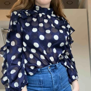  - Mörkblå blus med vita prickar från Zara. Den har volang på ärmarna och omsluts med 2 knappar i kragen. Aldrig använd. Frakt tillkommer. Skriv för mer info.
