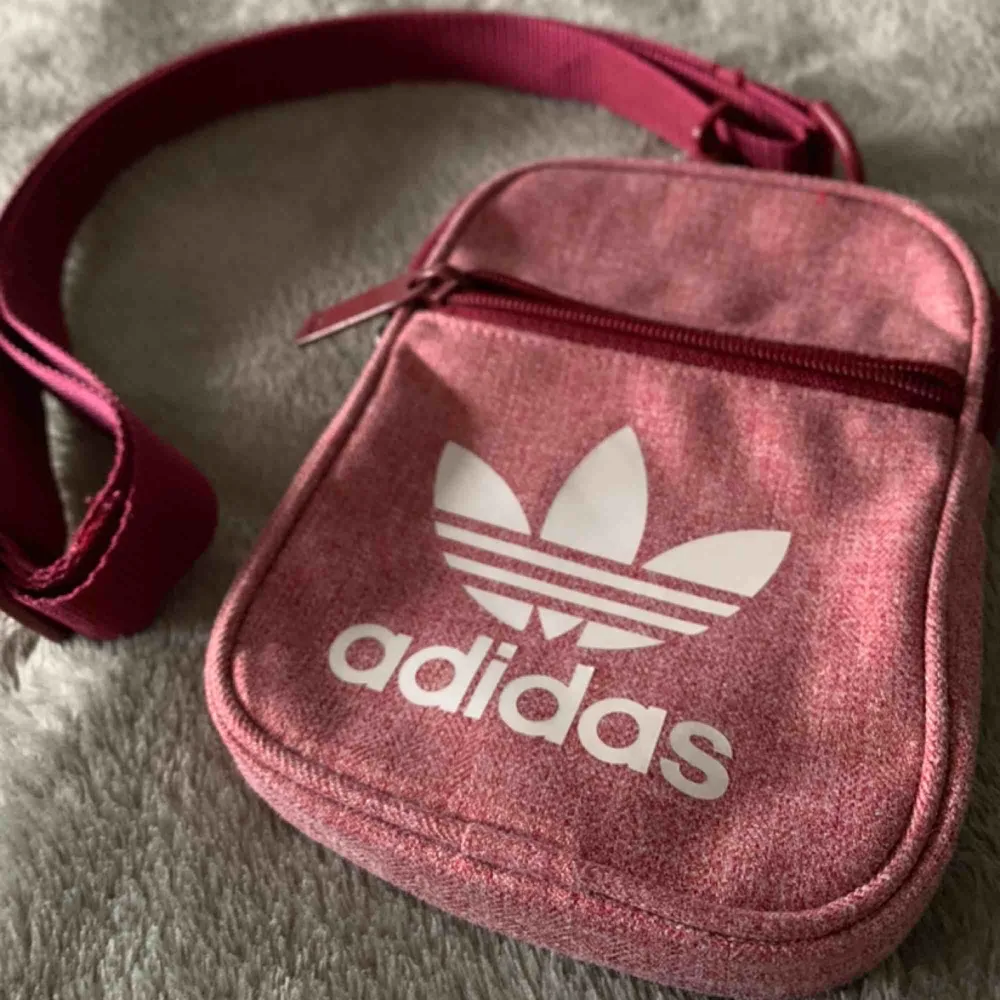 Vinröd, liten axelväska från Adidas. Perfekt storlek för mobil eller plånbok. Köpt i Teneriffa för 25€ för 1,5 år sen, endast använd ett par gånger. Fungerar i alla storlekar. 🥀🏔🥀🏔🥀🏔🥀🏔🥀🏔🥀🏔🥀🏔🥀🏔🥀🏔. Väskor.