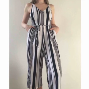  - Vid leverans: 200kr + frakt.  OBS: Egentligen storlek uk12 men den är insydd i midjan och bysten, därav storlek uk10.  Jumpsuit med knytning runt midjan. Vit med marinblå ränder. Använd 1 gång.  Ordinarie pris: 500