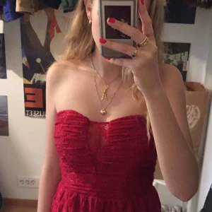  - Mörkare röd blommigt spets klänning. Dragkedja och hake på ryggen. Silikon ovanför brösten för att hålla uppe, funkar bra! Bara använd 1 gång. Slutar ovanför knäna.