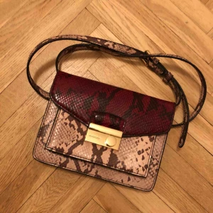  - Väska i syntetläder från Mango. Rosa och rött snakeprint.  Kan mötas upp i Sthlm eller skicka. Frakten står köparen för!  