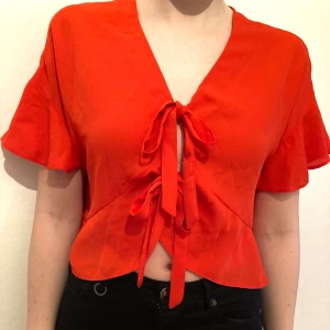Röd fin topp med knyt fram från ASOS - Röd fin topp man knyter fram, från ASOS. Storlek 36 men passar S-L beroende på hur man vill att den ska sitta då man knyter själv. Använd 2-3 gånger, fint skick. 