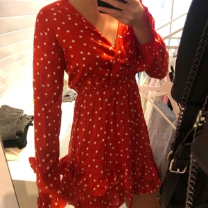 Röd prickig klänning från Linn Ahlborgs kollektion med Nakd - Klänningen är aldrig använd därav har den lappen kvar. Den är ganska lång trots att den är i storlek 32/34 då jag är ca 171 cm lång. Översta delen av klänningen är lite tajt. Köparen står frakt.