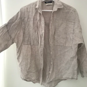 Linneskjorta Gina Tricot - Fin, välanvänd linneskjorta i beige. Ärmarna har krympt en aning i tvätt. Två slags fickor vid brösten. Fin att vika upp/knyta!