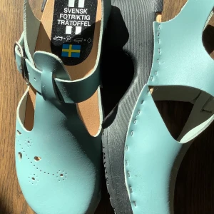 Svensktillverkade träskor 38 - Sköna träskor i skinn, turkos/ljusblått, mjuk gummisula, svart. Storlek 38, ca 23,5-24 cm, klackens höjd ca 5 cm. Hämtas Bromma el köpare bet frakt.