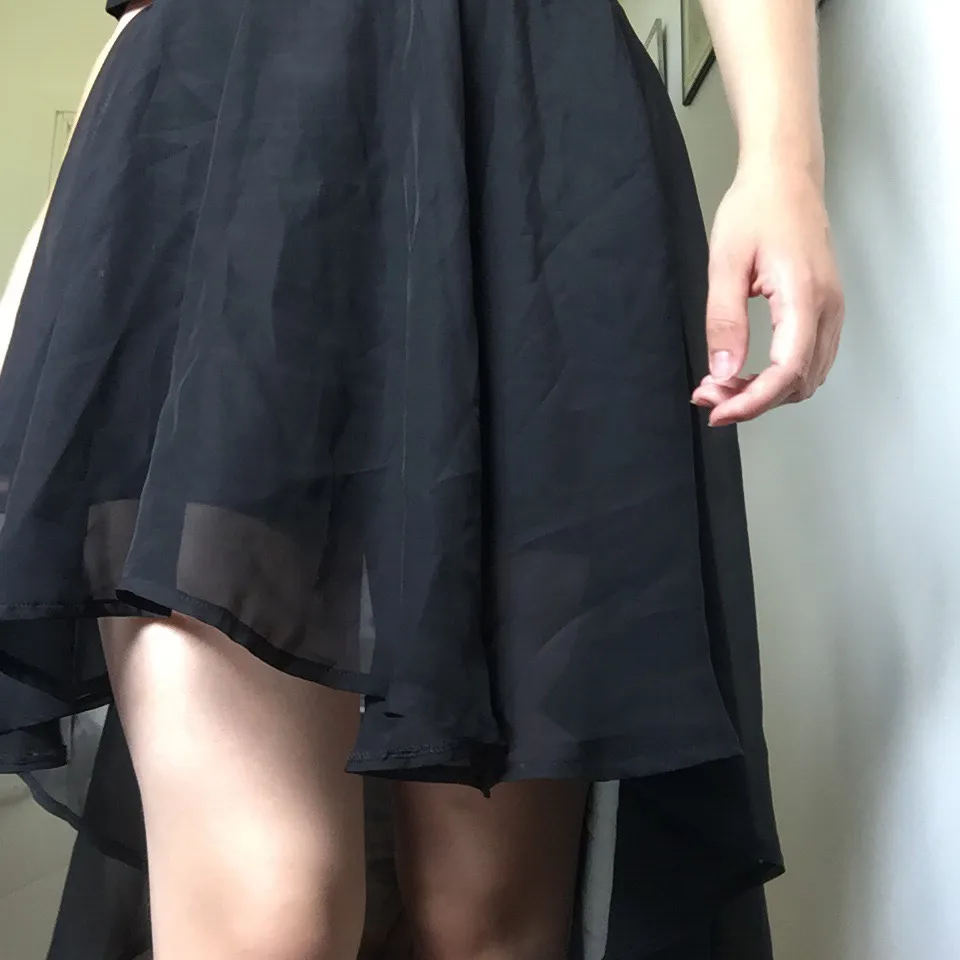Svart kjol i tunt tyg, längre bak och kortare fram. Kjolar.