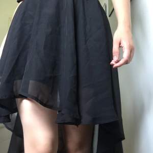 Svart kjol i tunt tyg, längre bak och kortare fram