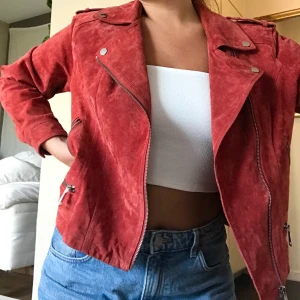 Mocka bikerjacka - Säljer min coola röda mocka biker jacka från Vero Moda då den ej passar längre. Använd 1 gång så den är i perfekt skick. Nypris låg på 800kr om jag ej minns fel. Köparen står för frakten