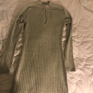 Klänning  - En fin grå klänning med en urring. Säljs bara i Helsingborg. Från Bik bok. Sitter väldigt fin på kroppen.