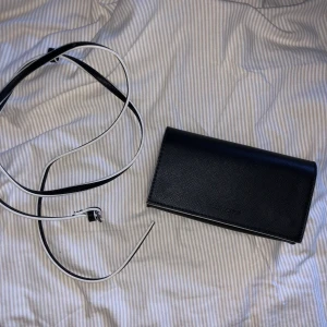 CARIN WESTER liten axelväska - Supersöt axelväska som rymmer en mindre plånbok, mobil och lite till. Medföljer justerbart band. Använd en gång men har ett litet vitt sträck på baksidan (se bild 3). Köparen står för frakt :) Pris kan diskuteras!