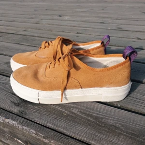 Orangea EYTYS sneakers i strl 39 - Orangea EYTYS sneakers med lila detaljer i strl 39. Perfekta till sommaren!! I använt, men bra skick (slitna vid märket, se bild). Jag tar 450 kr + frakt (63 kr), nypris är 1700 kr. Samfraktar självklart om du köper mer! 