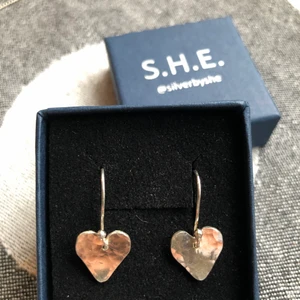 Örhängen i äkta silver - Trevliga hammrade silverörhängen, hjärtformade, på en ögla. Hjärtats höjd är 12mm. Med hela kroken blir höjden 24 mm. Direkt från silversmed @silverbyshe.
