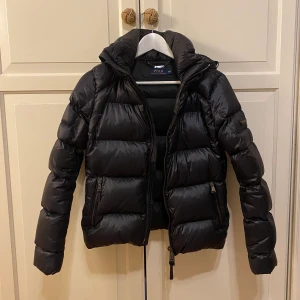Svart dunjacka - 🍒🍒 Säljer min Ralph Lauren dunjacka i storlek XS! Den är i mycket bra skick och har inga slitningar. Luvan går även att ta av! Köpt är köpt och lägsta bud ligger på 250kr
