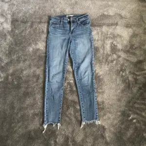 Säljer ett par blå Levis jeans i modell 721 med slitningar nertill. Använda men i bra skick. Storlek 26. Skriv för fler bilder. 