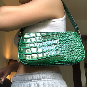 Grön shoulderbag - Smaragdgrön väska i fejk ormskinn med guld detaljer. Bra skick! Köparen står för frakt🦋  