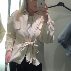 Perfekta vita vårjackan! - Jacka med fina knytdetaljer som ger en fin passform! Den är knappt använd. Frakten blir spårbar enligt PostNord, och köparen betalar frakten. 