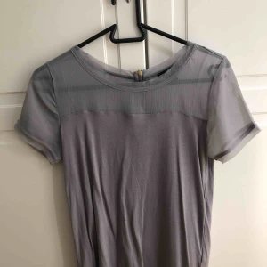  - Fin t-shirtblus med meschtyg upptill och dragkedja på baksidan! Fin grålila färg! Nyskick.  Köpare står för frakt!