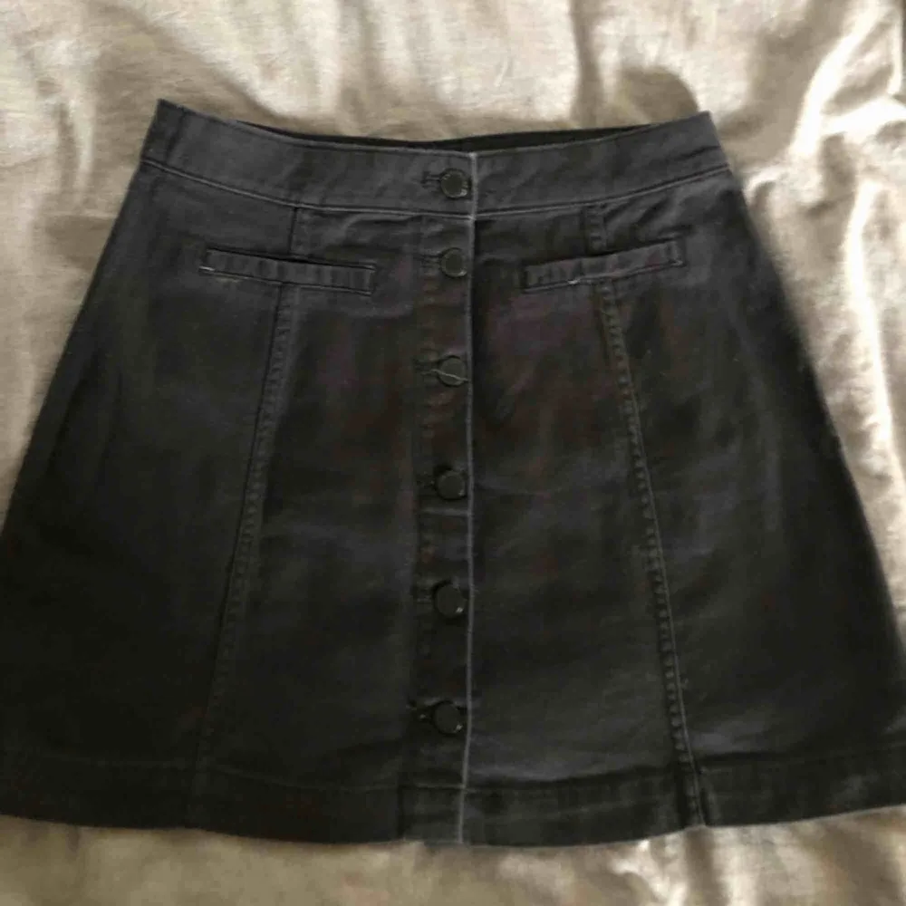 Fin svart jeans kjol med knappar och fusk fickor på vardera sida, kjolen kommer från hm och är använd högst 3 gånger. . Kjolar.