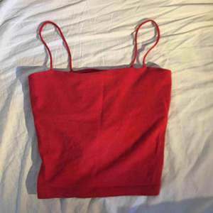 Ett rött linne med spagettistraps från gina, linnet är lite kort så det är nästan en magtröja, köparen står för frakten
