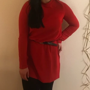 Röd klänning - Röd långärmad rak klänning som man kan styla med fin skärp. Använd en gång.
