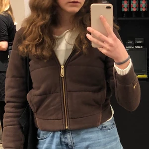 Nike brun hoodie - Brun liten Nike zip up hoodie!🔥 har konturer likt puffer jacket. Nike märket syns på ärmen och dragkedjan. Har en luva. 