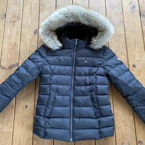 Svart Tommy Hilfiger vinterjacka - Svart Tommy Jeans vinterjacka i storleken M. Jackan har två stycken fickor och en avtagbar luva. Jackan har en väldigt fin och mjuk fuskpäls. Den är använd ett fåtal gånger och är i fint skick. På vänster sida bröst och vänster arm finns Tommy Hilfiger loggan. Köpt på Nellys hemsida. Ordinarie pris 2500 på Nelly.com. (Kontakta för mer bilder) Swish