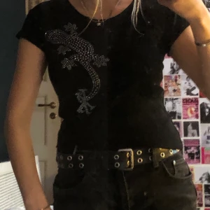 Svart tröja med ödla! - Svart topp med ödletryck i strass! Köpt second hand och är i jättefint skick. Köparen står för frakten<3
