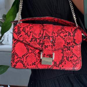 As cool väska från Zara i en neon röd/orange färg med ormskinnsmönster. Väskan har silvriga detaljer, och den kan bäras på flera sett. Den är i fint skick. Frakt tillkommer💛