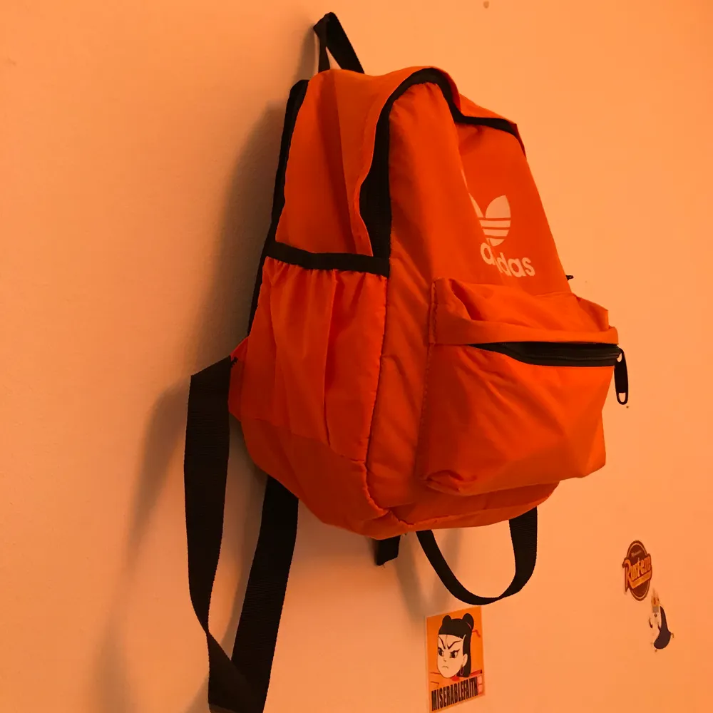 En mini Adidas ryggsäck i neonorange färg. Ingen aning om det är fejk eller äkta. Använd 1 gång och är så gott som ny. Säljer för 90kr + frakt🧡🧡 Priset går att diskuteras.. Väskor.
