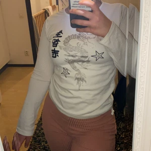 Tröja med drake  - En vit tröja med kinesiska tecken , stjärnor och en silverglittrig drake på framsida. Kan dras åt vid midjan snören (Bild 3) . Storlek 170 men sitter som Xs/s 