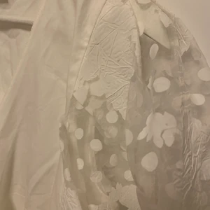 Vit blus med spets - Jättesöt vit blus med omlottknyte och puffärmar i spets med fin design på, från märket VISUAL CLOTHING PROJECT. Den sitter jättefint på men för mig är den lite för stor då jag vanligtvis är en xs, och därför säljer jag den nu. Den är provad men aldrig använd! 