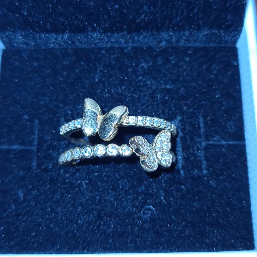 Guld platerat ring med fjärilar, är osäker på storlek. OBS lådan i bilden medföljer ej. Accessoarer.